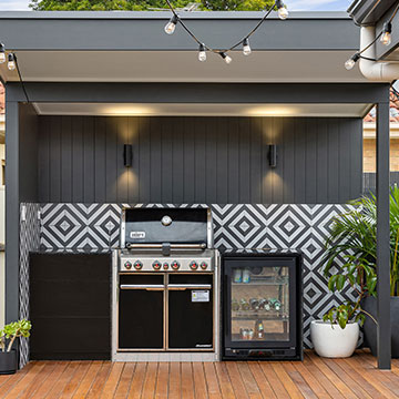 Front view of outdoor kitchen on wood floors with plants